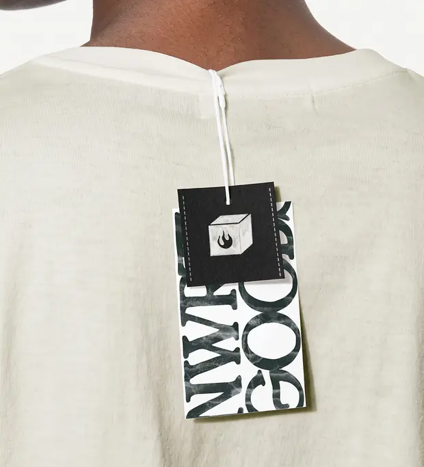Tag da marca com o cubo em chamas pendurada na nuca de uma camiseta off-white
